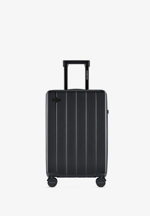 Black hard-shell suitcase with vertical ribbed texture, retractable handle, and four spinner wheels for easy mobility.