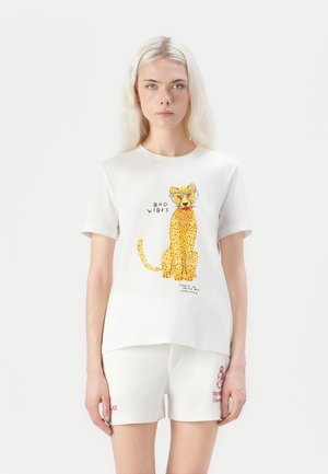 Vit bomulls-t-shirt med en gul leopardgrafik och text i svart. Korta ärmar och en avslappnad passform; matchas med vita shorts.