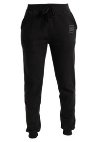 Black sweatpants made from soft fabric featuring an elastic waistband, drawstring, side pockets, and a small logo patch on the hip.