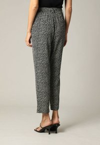 Zwart-wit gestreepte broek met een elastische tailleband, cropped silhouet en lichtgewicht stof, gestyled met open teen hakken.