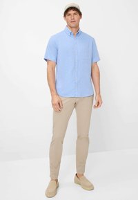 Korte mouw lichtblauw overhemd met knopen en kraag, met een voorzak, gecombineerd met beige slim-fit broek en beige instap schoenen.