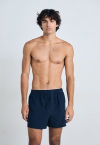 Boxers de algodón azul marino con cinturilla elástica, que presentan un cierre de botón en la parte delantera y una textura suave y lisa.