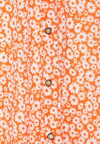 Oransje blomstret kjolestoff med hvite tusenfryd mønstre, med en rad av brune knapper foran, teksturert bomullsmateriale.