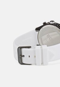 White silicone strap watch with a black metal clasp, featuring a circular face and polished glass, marked as water-resistant.