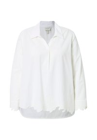 Blusa bianca con maniche lunghe, colletto a punta e lunghezza sotto i fianchi. Presenta un'intricata ricamo floreale all'orlo. Tessuto texturizzato.