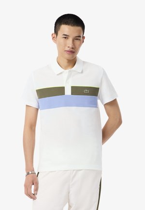 Weißes Poloshirt mit olivgrünen, blauen und hellgrünen horizontalen Streifen, mit einem kleinen Logo auf der linken Brustseite. Kurze Ärmel.