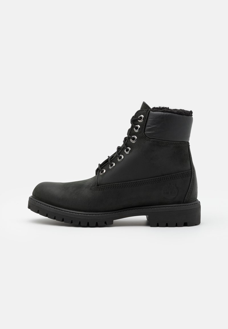 Zwarte leren enkellaarsjes met een gestructureerde afwerking, robuuste zool en metalen vetergaatjes, voorzien van een zachte fleece voering bij de kraag.