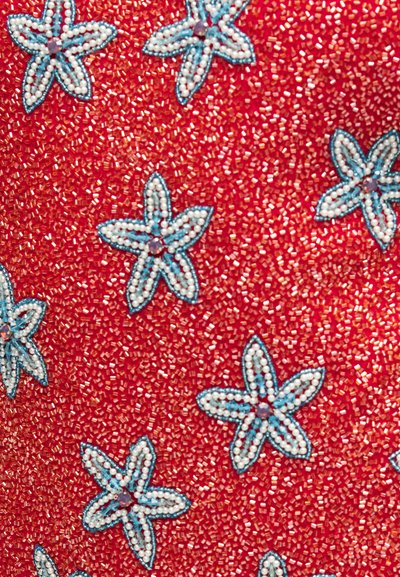 Κόκκινο ύφασμα πυκνά καλυμμένο με μικρές χάντρες και διακοσμημένο με λευκά και μπλε λουλούδια σε σχήμα αστεριού από χάντρες.