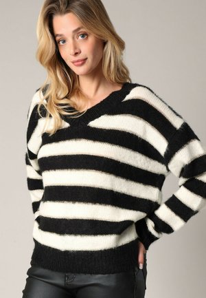 Pull à rayures noir et blanc avec un col en V, fabriqué en tissu doux ; comporte des manches longues et une coupe décontractée. Design tricoté texturé.