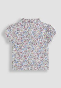 Kurzarm-Hemd mit Kragen, das aus einem weißen Stoff besteht, der mit kleinen rosa, blauen und gelben Blumenmustern bedeckt ist. Glatte Textur, leichtes Design.