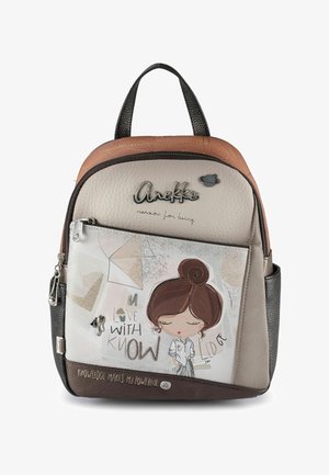 Rucksack mit einer Illustration eines Cartoon-Mädchens, Text „Verliebt in Wissen“, braune und beigetöne, vordere Reißverschlusstasche und schwarzer Tragegriff.