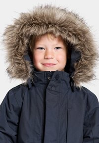 Marinblå parka med huva av faux päls, med dragkedja och tryckknappar, samt ett slitstarkt, texturerat yttertyg.