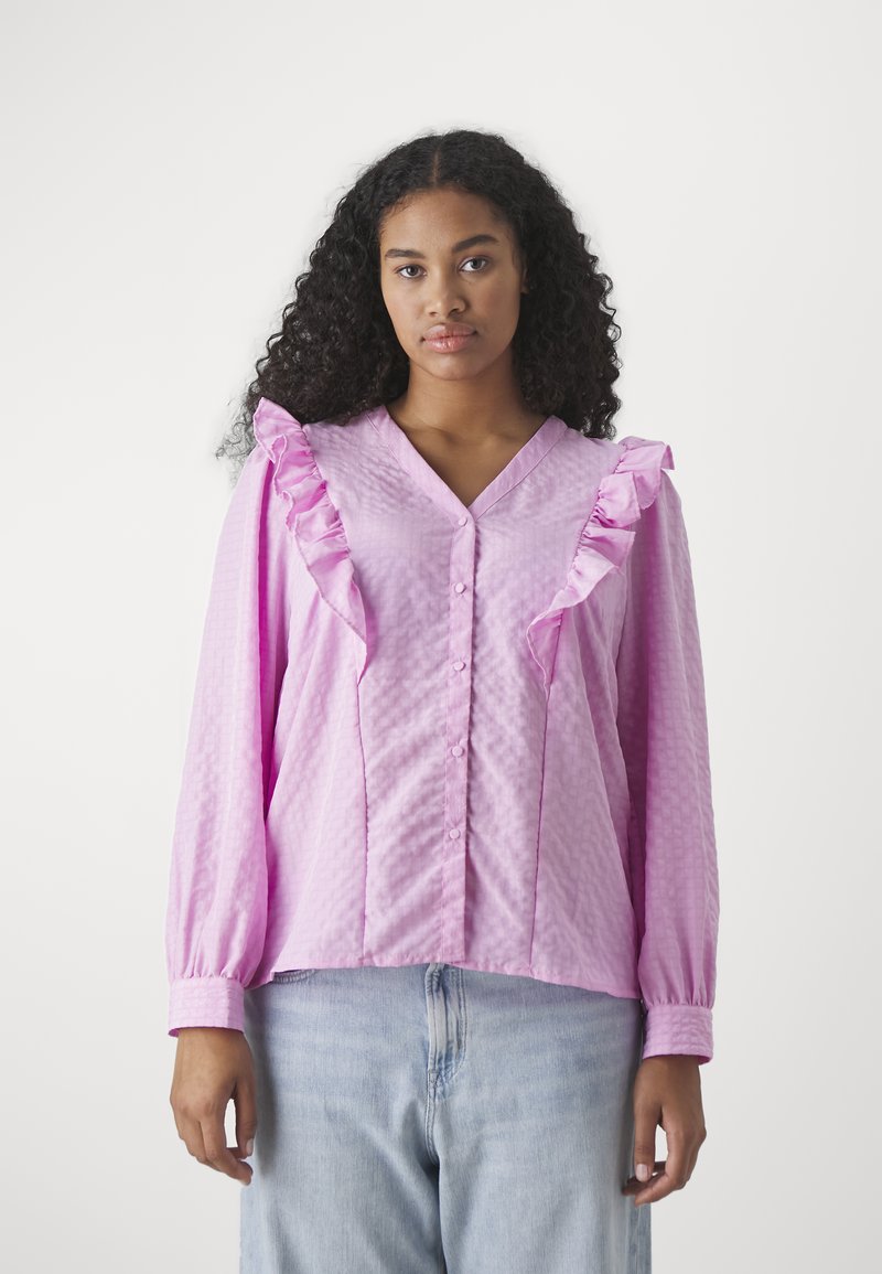 Blusa rosa con dettagli arricciati sulle spalle, chiusura a bottoni e maniche lunghe. Realizzata in tessuto testurizzato con una vestibilità comoda.