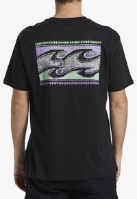Camiseta de algodón negra con un diseño gráfico vibrante que presenta olas moradas y verdes en el centro, contorneadas con un borde geométrico.
