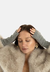 Szare bezpalczaste rękawiczki dziane o prążkowanej fakturze, noszone z futrzanym płaszczem. Rękawiczki są dopasowane i sięgają do przedramion.