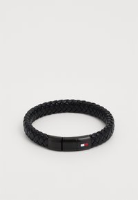 Bracelet en cuir tressé noir avec un fermoir lisse arborant un petit logo coloré. Le design est rond et texturé dans son intégralité.