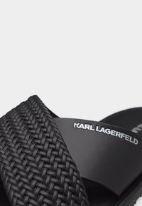 Μαύρο σανδάλι slide με πλεγμένο διασταυρούμενο λουράκι υφής και λείο λουράκι που διαθέτει λευκή επιγραφή με το λογότυπο "KARL LAGERFELD".