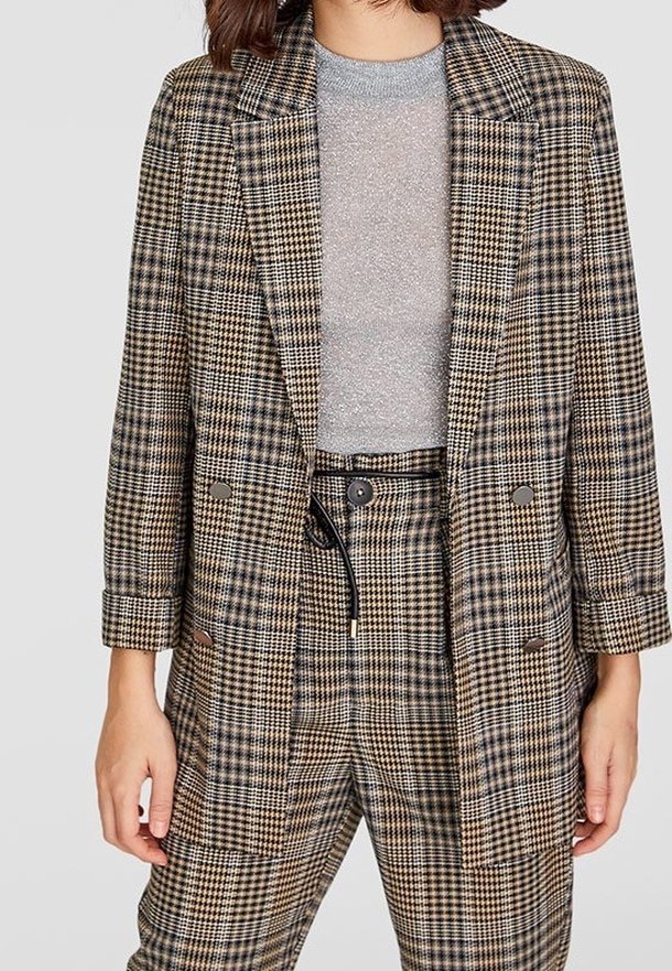 Dvoudílný kostkovaný blejzr v hnědé, béžové a námořnické modři. Podšitý, s klopovým límcem a velkými knoflíky. Nosený přes světle šedý top.