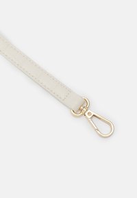 Vit konstläderrem med en strukturerad design, försedd med en guldfärgad metallklämma för fäste.