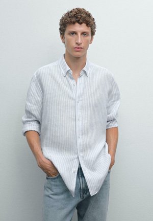 Lichtgrijs gestreept shirt met lange mouwen, button-down kraag en opgerolde manchetten, gecombineerd met licht denim jeans. Soepele textuur.