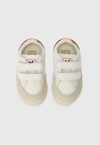 Hvide lædersneakers med to velcroremme, beige ruskindsdetaljer og farverigt mønster på hælen. Rundet tå og struktureret gummisål.