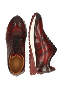 Mörkröda läderbroguesneakers för män med svarta snören, perforerade detaljer och tjocka, texturerade gummisulor, visade från ovan och sidan.