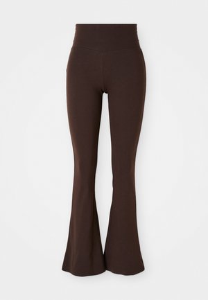 Brune uitlopende leggings gemaakt van zachte, rekbare stof, met een hoge tailleband en een getailleerd silhouet dat uitloopt bij de enkel.