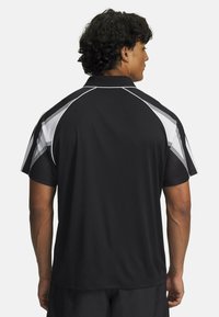 Polo negro atlético de manga corta, con acentos diagonales blancos y un diseño texturizado en los hombros y la espalda.