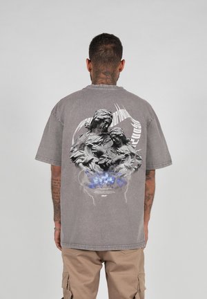 Gray oversized t-shirt featuring a graphic print of two sculptural figures on the back, with blue accents and lightning motifs.