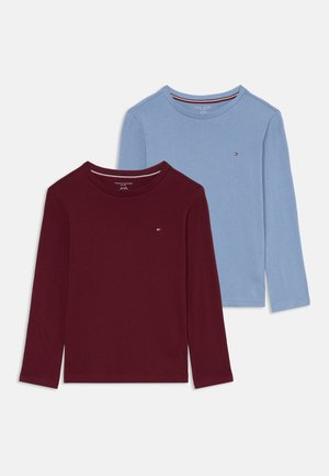 Deux T-shirts à manches longues : l'un en rouge foncé et l'autre en bleu clair, tous deux en coton doux avec un col ras du cou et un petit détail de logo.