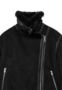 Giacca in suede nera con dettagli in pelle, caratterizzata da un colletto alto, una fascia con fibbia e due tasche con zip per riporre oggetti.