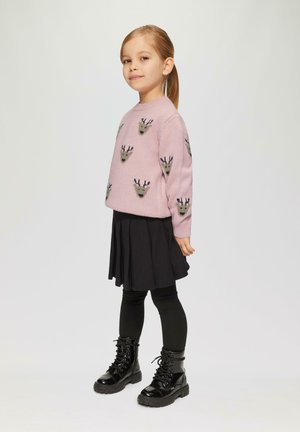 Pull en tricot rose clair avec des motifs animaliers, jupe plissée noire, legging noir et bottes à lacets noires brillantes. Texture lisse.