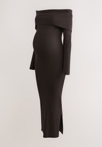 Schulterfreies, geripptes Umstandskleid in Dunkelbraun, mit langen Ärmeln und einem seitlichen Schlitz für mehr Bewegungsfreiheit.