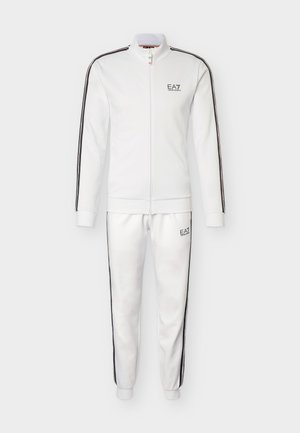 Balta pilnos užtrauktuko sportinė apranga su juodomis šoninėmis juostomis, EA7 Emporio Armani logotipu ant krūtinės ir šlaunies, su ribinėmis rankogaliais ir apykakle.