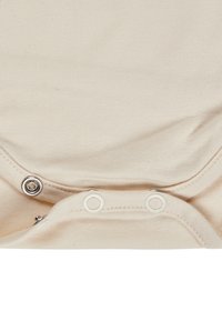 Snap fasteners on beige cotton fabric, partially open, showing details of stitching and metal rings.