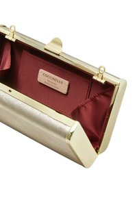 Clutch de cuero metálico dorado con exterior texturizado, forro de satén rojo y cierre de broche rectangular. Incluye una etiqueta de autenticidad.