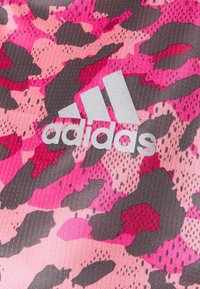 Tejido atlético de Adidas con un diseño de estampado de leopardo en rosa y gris, con un logo plateado. La textura parece suave con un ligero brillo.