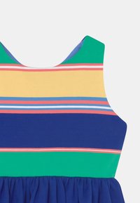 Ärmlös klänning med horisontella ränder i grönt, gult, rosa och blått. Mjuk tyg, rundad halsringning och rynkad blå kjol.