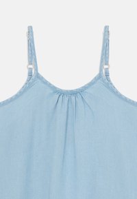 Svijetloplavi chambray top s tankim podesivim trakama, nabranim izrezom i mekanom teksturom. Šavne detalje uz rubove.