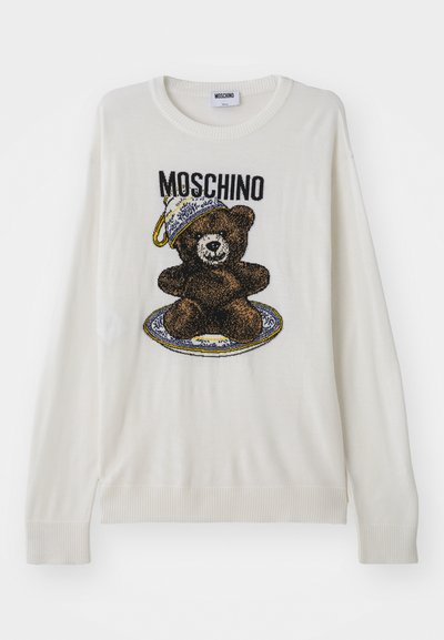Weißer Strickpullover mit einem Bärenmotiv, der einen Hut und einen Teller trägt, mit schwarzen und braunen Details sowie gerippten Bündchen und Saum. Moschino-Etikett sichtbar.
