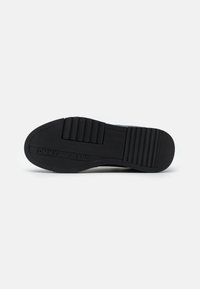 Suola di sneaker nera in gomma con motivo a zigzag, caratterizzata dal logo "TOMMY JEANS" e da sporgenze testurizzate per una migliore aderenza.