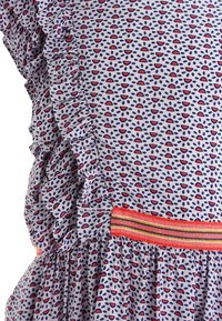 Lyseblå stofkjole med rød og marineblå tåreformet mønster. Har volanger langs kanten og et flerfarvet elastisk taljebånd.