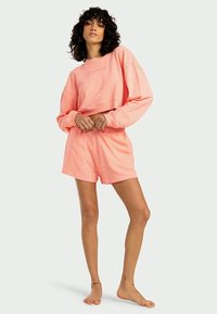 Sweatshirt cropped em rosa e calções combinados. Feito de tecido macio com textura canelada. Corte solto, mangas compridas e cintura elástica.