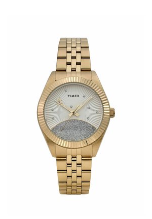Reloj de pulsera Timex en tono dorado con esfera inferior de purpurina plateada, segundero en forma de estrella, marcadores de hora de cristal y pulsera metálica enlazada.