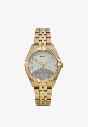 Auksinio tono Timex riešo laikrodis su sidabro blizgučiais apatinėje ciferblato dalyje, žvaigždės formos sekundine rodykle, kristalų valandų žymekliais ir sujungtu metaliniu apyrankės dirželiu.