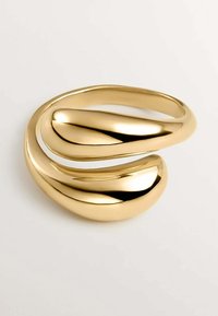 Pulsera de metal en tono dorado con una superficie lisa y elegante. Presenta un diseño ondulado con tres curvas interconectadas.