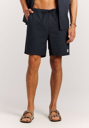 Donkerblauwe zwemshorts met een elastische tailleband en verstelbare trekkoord; voorzien van twee zijzakken en een klein logoplaatje.