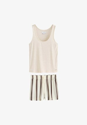 Vrouw met lang donker haar die een lichtgrijze mouwloze tanktop draagt en opzij kijkt tegen een effen achtergrond.