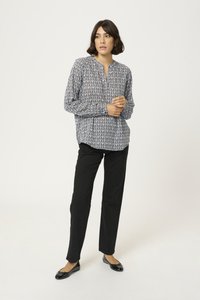 Blusa a maniche lunghe, a righe blu e bianche, con scollatura senza colletto, abbinata a pantaloni neri a gamba dritta e ballerine nere.