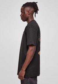 Sort bomulds T-shirt med korte ærmer, med grafisk tryk på ryggen, afslappet pasform og rund halsudskæring.